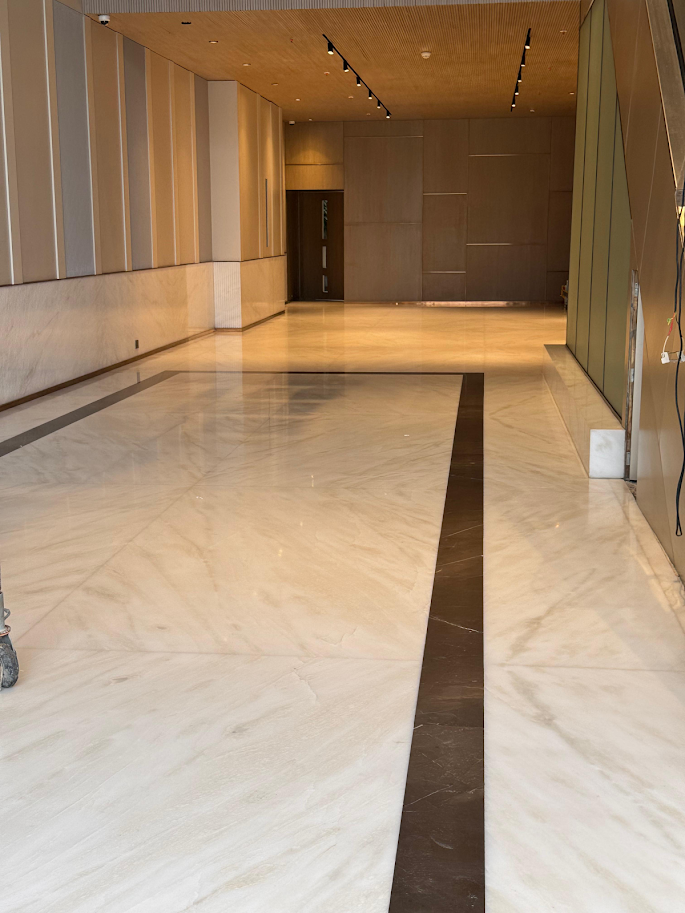 Spacious, modern lobby featuring polished marble floors and sleek wooden paneling, highlighting contemporary design elements.