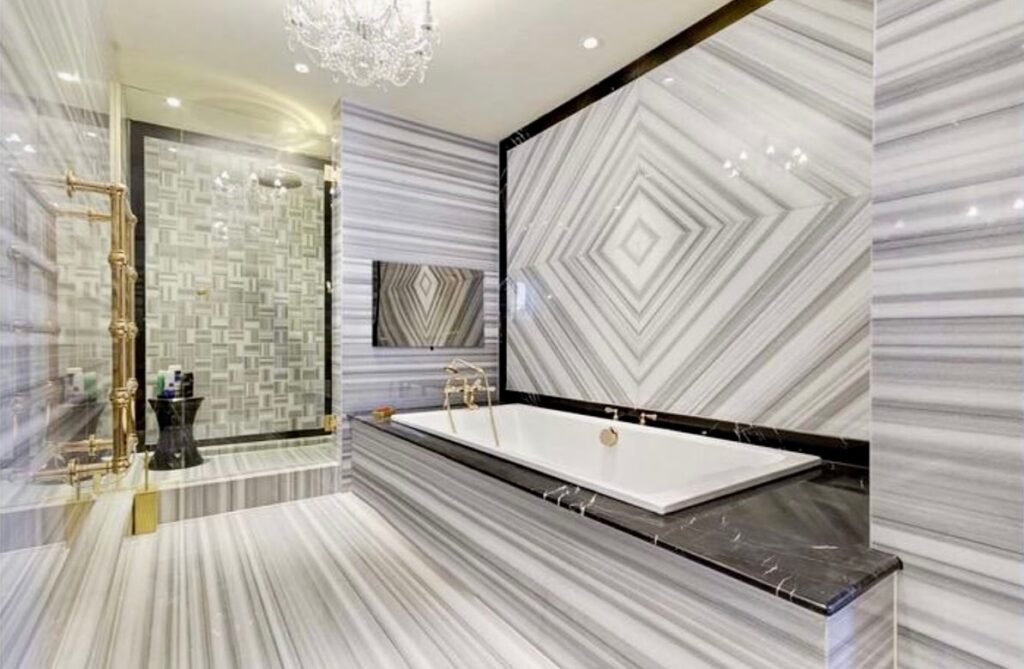 Luxurious bathroom featuring marble walls, a freestanding tub, and elegant gold fixtures.