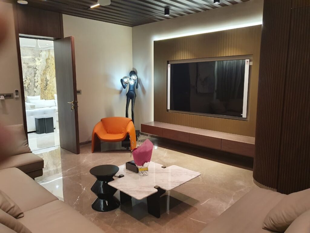 Modern living room featuring an orange chair, sleek furniture, and a wall-mounted TV, showcasing contemporary design.