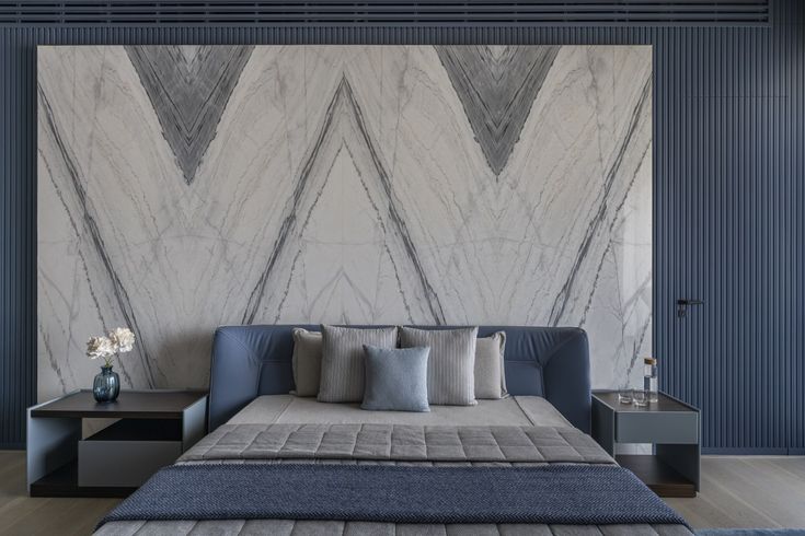 Modern bedroom featuring a geometric marble accent wall, stylish bedding, and minimalist furniture.