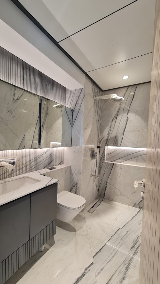 Modern bathroom featuring marble walls, sleek cabinetry, and contemporary fixtures, showcasing elegant design elements.
