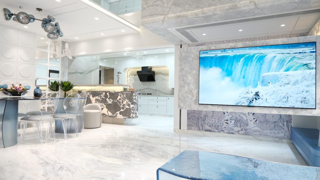 Modern kitchen and living area featuring sleek furnishings, marble accents, and a large screen displaying a waterfall.