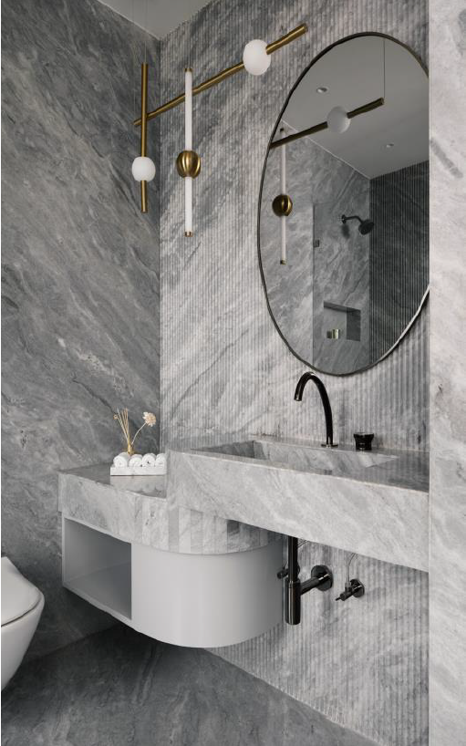 Modern bathroom design featuring gray marble walls, a sleek sink, and stylish lighting fixtures.