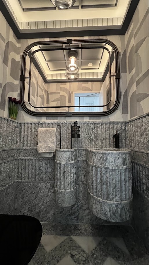 Stylish bathroom featuring marble sinks, modern fixtures, and decorative wallpaper, showcasing elegant design elements.